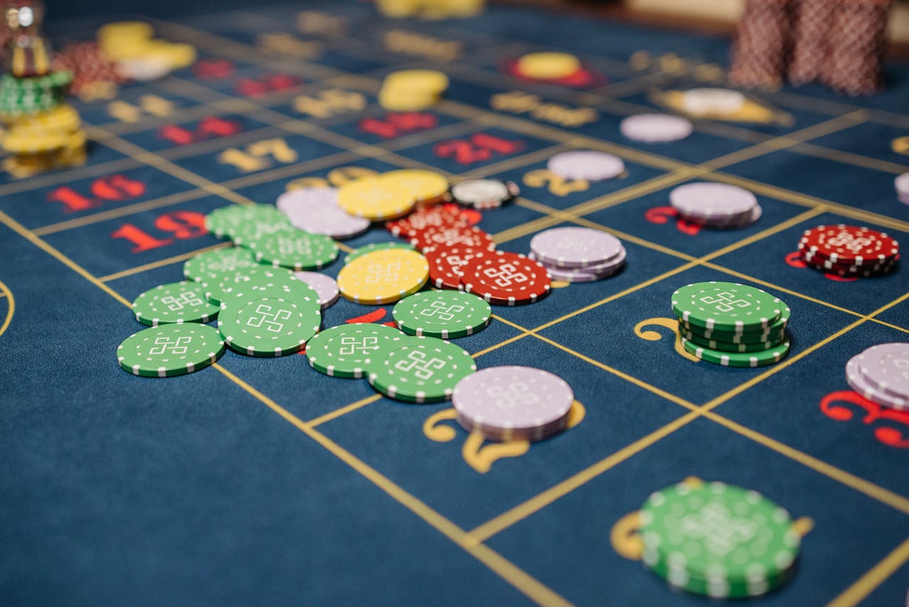 Closeup of colorful casino chips scattered on a roulette table.